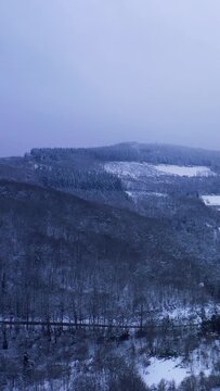 Vertical 9:16 aerial video showing a sweeping view over the snow-covered forests and rolling hills of the Morvan region at Haut Folin in Bourgogne-Franche-Comte, France.