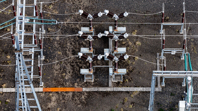 Aerial view of the Krokslon electrical power station featuring high-voltage equipment, metal structures, and insulators set against a dark volcanic ground in Iceland.