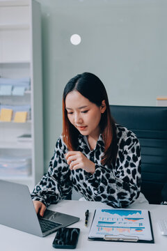 Office Discomfort: A female office worker in a red shirt experiences neck pain while working on her laptop, surrounded by office supplies and a calculator, indicating a stressful work environment.