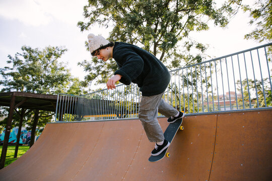 Young skateboarder perform trick on outdoor skate ramp
