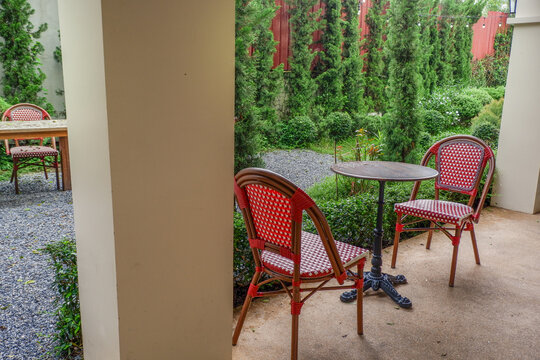 Luxury chair and wooden table set in english garden on a sunny day,outdoor seating for restaurant or cafe,Near paver patio with sitting area and small garden in forest.
