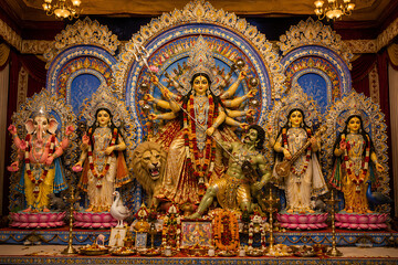 Fototapeta premium Elaborate Durga Puja Pandal Displaying Goddess Durga Defeating Mahishasura Surrounded by Ganesha, Lakshmi, Saraswati, and Kartikeya During Navratri Festival Celebrations