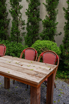 Luxury chair and wooden table set in english garden on a sunny day,outdoor seating for restaurant or cafe,Near paver patio with sitting area and small garden in forest.