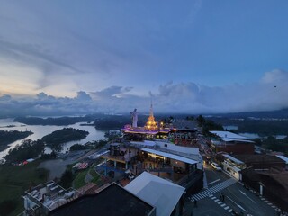 Naklejka premium Hilltop complex and illuminated temple at dusk overlooking a reservoir