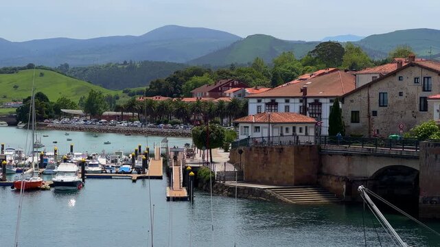 San Vicente de la Barquera coastal town panning view, Cantabria Spain, historic bridge, marina boats and green hills. High quality 4k footage