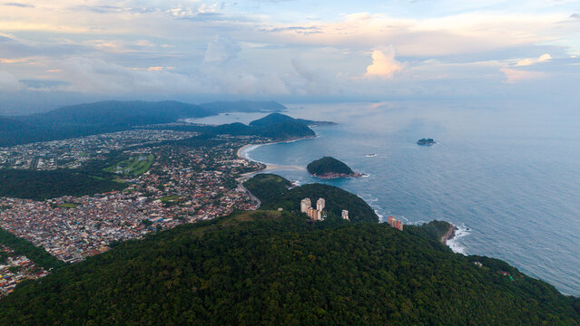 Aerial view of Pernambuco Beach and the surrounding coastal landscape with lush green hills, residential buildings, and the Atlantic Ocean in Guaruja, State of Sao Paulo, Brazil.