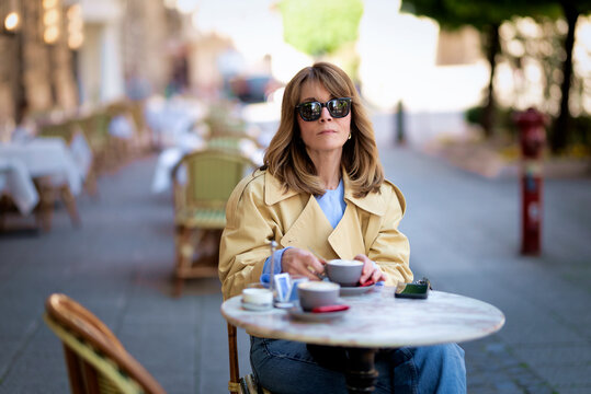 Confident middle-aged woman sitting at a traditional European street cafe