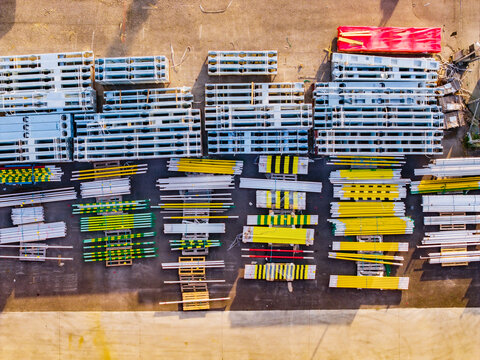 Aerial view of organized rows of metal pipes and construction materials stored on pallets in a yard in Noventa di Piave, Veneto, Italy.