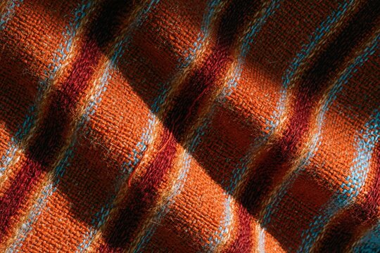 Woven cloth surface with red diagonal stripes and honey gold tones, featuring tactile slubbed yarn and fiber fuzz for fashion and textile backgrounds