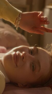 Vertical portrait of Caucasian teenage girl lying down, twirling her ginger hair and smiling at camera. Clip is suitable for youth mental health awareness or hair care commercials