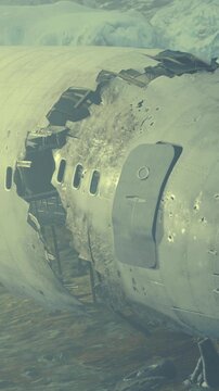 An airplane lay wrecked on a snowy ground near large ice formations in a remote location. The front of the plane shows signs of damage from the crash. The scene looks cold and deserted.