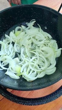 Chef salting sliced onions in a paella pan