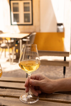 hand swirling natural wine in a glass on a wood table on a narrow picturesque street in europe