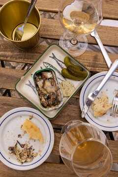 overhead view of meal in Portugal of tinned sardines, pickles, bread, and wine on outdoor wood table
