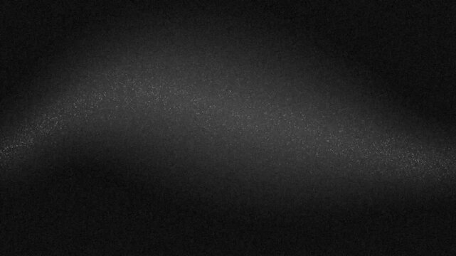 Fine gray particles create a soft grainy texture across a dark background, producing a subtle atmospheric visual.