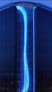 Glowing blue light streaks moving down tall modern glass building facade in this digital.