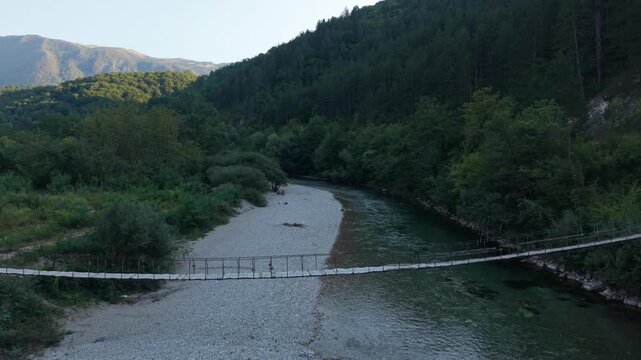 Drone Aerial View Flying Towards Wooden Suspension Footbridge Over Shallow Neretva River and Exposed Pebble Bed