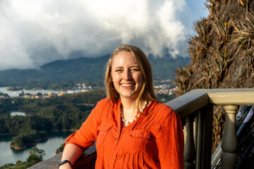 Naklejka premium Smiling woman on mountain terrace overlooking lake and town