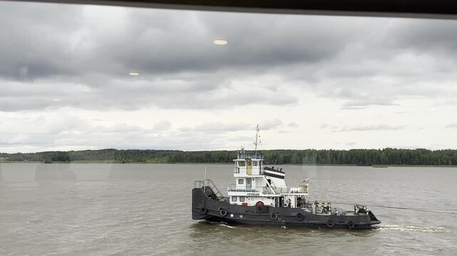UGLICH, RUSSIA &ndash; JULY 26, 2020. View from a cruise ship of a tugboat on the Volga River in gloomy, overcast weather.
