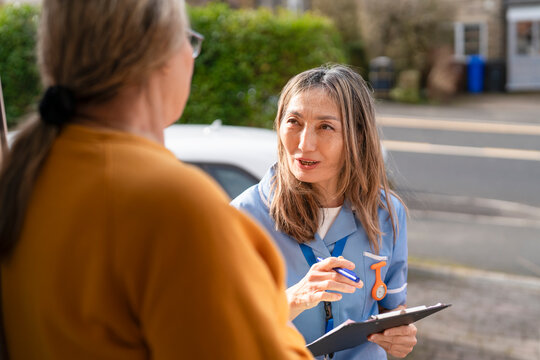Health worker talks to a person at their home during a community health visit in the neighborhood