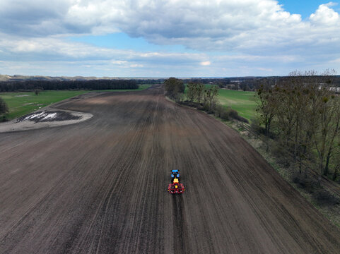 Aerial view of a tractor working on a large plowed field near Wriezener Alte Oder in Brandenburg, Germany.
