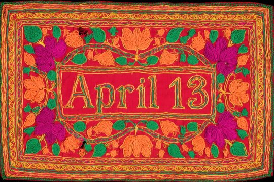 Richly embroidered Punjabi Phulkari textile featuring April 13 in vibrant yellow, surrounded by intricate floral motifs on a crimson background, showcasing traditional craftsmanship