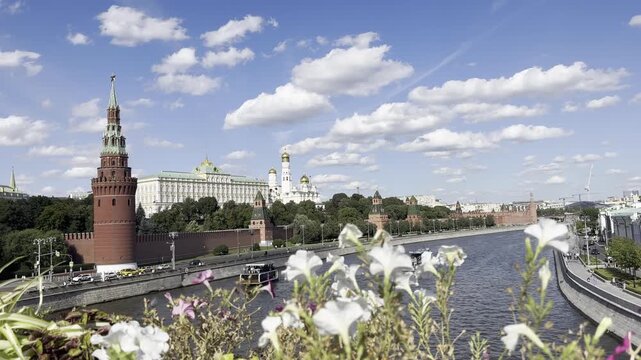 Moscow, Russia, August 24, 2025. View of the Kremlin from the Moscow River, framed by flowers on the bridge, with sightseeing boats cruising along the canal.