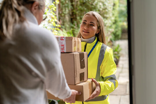 Delivery person hands over packages at a home entrance during daylight hours