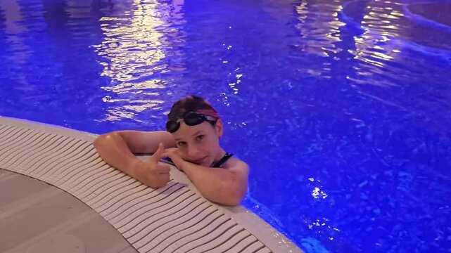 Child swims in pool at night under blue lights