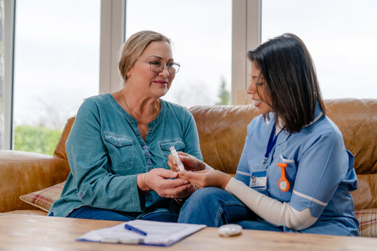 Nurse demonstrates health check to patient at home in bright living room setting