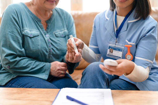 Nurse shows patient how to use a glucose meter at home during a health check