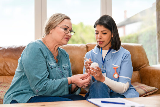 Nurse explains medication use to elderly patient in a home setting
