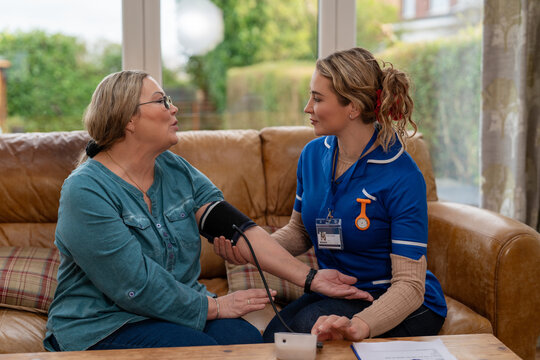 Nurse checks blood pressure of patient at home during visit