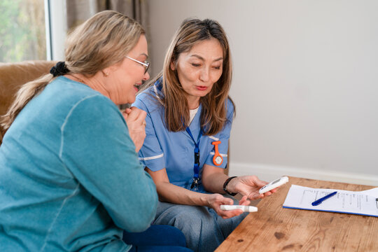Two women discuss care options while sitting at a table in a home setting
