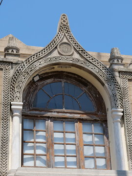 Ornate stone arch with braided carvings over a historic wooden window