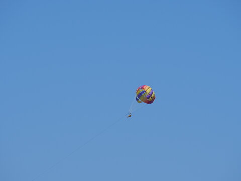 Colorful parasail wing soaring in a clear sky with copy space