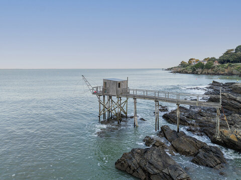 Aerial view of a traditional wooden fishing hut on stilts over the rocky coastline of the Atlantic Ocean in Pornic, Pays de la Loire, France.