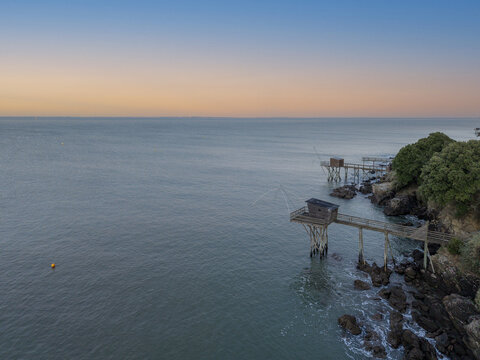 Aerial view of traditional wooden fishing huts known as carrelets perched on stilts over the rocky coastline of Pornic, Pays de la Loire, France.