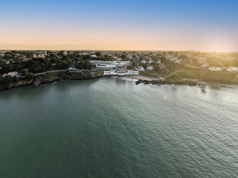 Aerial view of the coastal town of Pornic with its historic buildings, rocky shoreline, and calm sea during the golden hour in Pornic, Pays de la Loire, France.