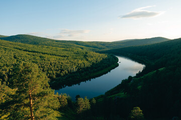 Fototapeta premium Meandering river cutting through green forested hills at daylight, Chita Transbaikalia nature of Russia