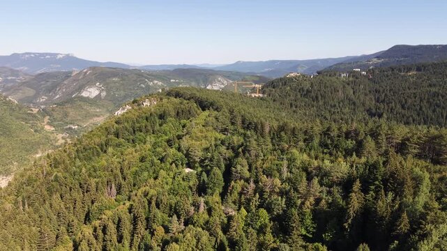 Drone Aerial View Flying Over Dense Trebevic Forest Revealing Construction Cranes and Mountain Panorama