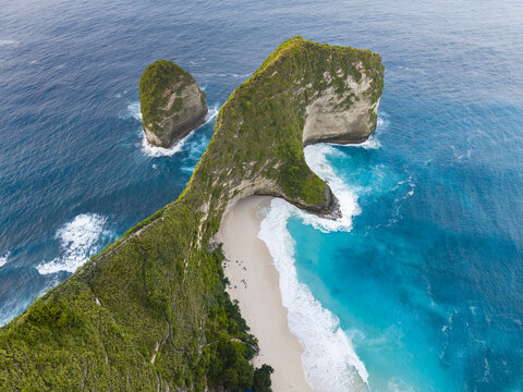 Aerial view of Kelingking Beach with its iconic T-Rex shaped cliff formation, turquoise waters, and crashing waves in Nusa Penida, Bali, Indonesia.