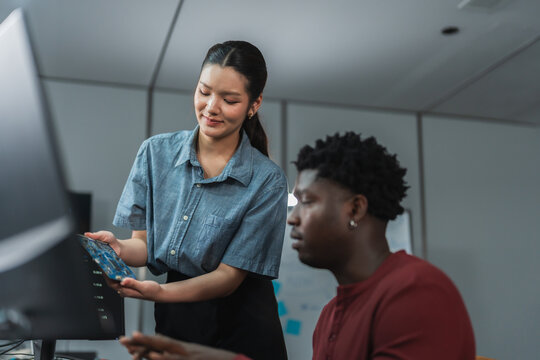 Female developer guides male colleague through collaborative research and development project, demonstrating educational mentorship and knowledge transfer in AI-assisted learning environment.