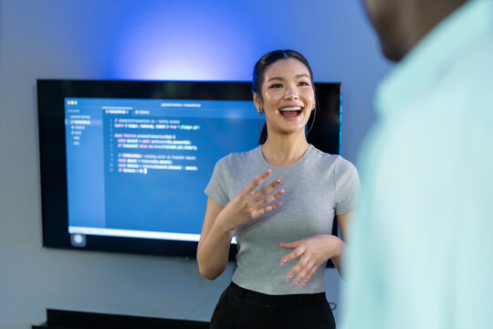Asian female developer presents code review insights and feedback to team, demonstrating technical leadership and collaborative code discussion with colleagues.