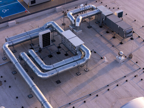 Aerial view of HVAC systems and metallic ventilation ducts on a flat rooftop in Gdansk, Poland.