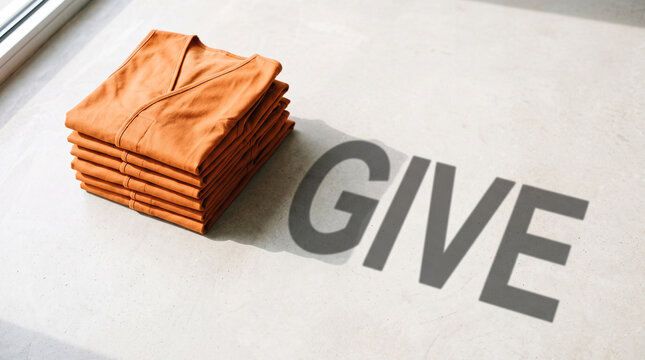 A neat stack of folded orange vests placed on a flat surface with the word give with rests light surface give cast shadow philanthropy humanitarian organization with contribution