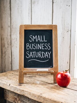 Small business Saturday promotion on rustic wooden table with chalkboard
