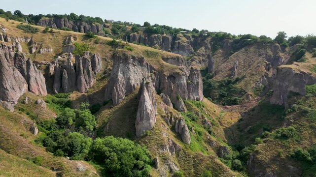 Aerial footage over the abandoned Khndzoresk cave settlement in southern Armenia, showing former homes carved into the steep rock cliffs and scattered across the canyon landscape.