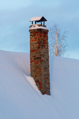 Fototapeta premium Snow-covered brick chimney stands tall against winter sky