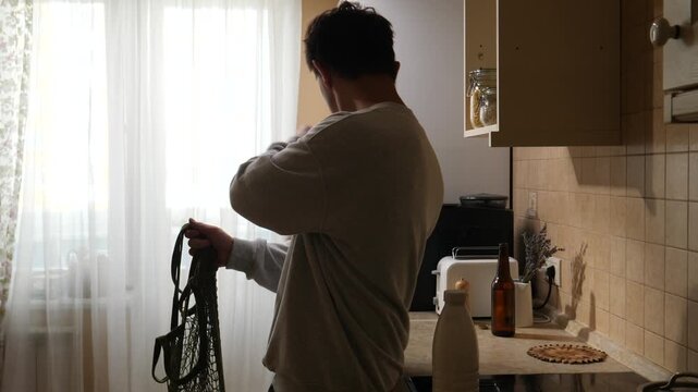 Vertical video man standing in a modern kitchen, viewing a digital recipe on a tablet screen, embodying digital lifestyle and smart home technology while preparing a meal